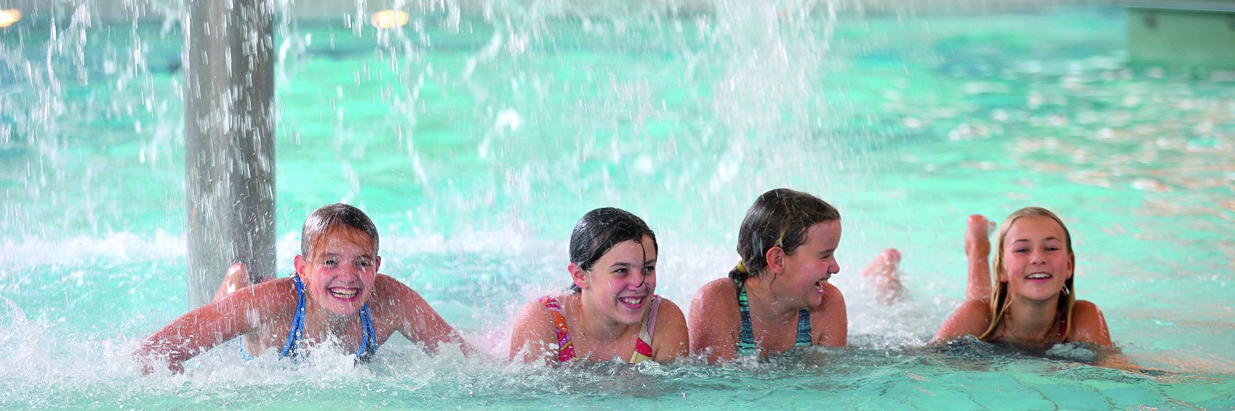 vier mädchen liegen unter einem regenpilz im erlebnisbereich im erlebnisbad laola